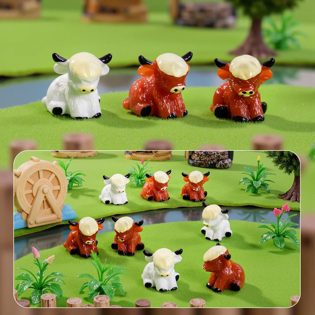 A collection of adorable resin Highland cow figurines in white and orange colors displayed on a green surface.