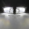 A pair of clear LED fog light assemblies mounted on a vehicle, shining bright light onto a surface.
