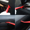 Primeros planos de una herramienta roja para aplicar película tintada en el interior de un coche negro.