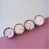 A collection of silicone molds shaped like daisies in pink and cream colors displayed on a pink surface.