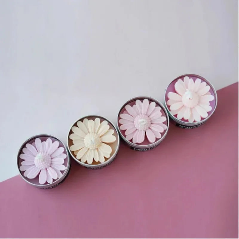 A collection of silicone molds shaped like daisies in pink and cream colors displayed on a pink surface.