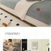 Housse de canapé sherpa gris clair avec accents beige et pompons décoratifs, présentée dans un salon moderne.