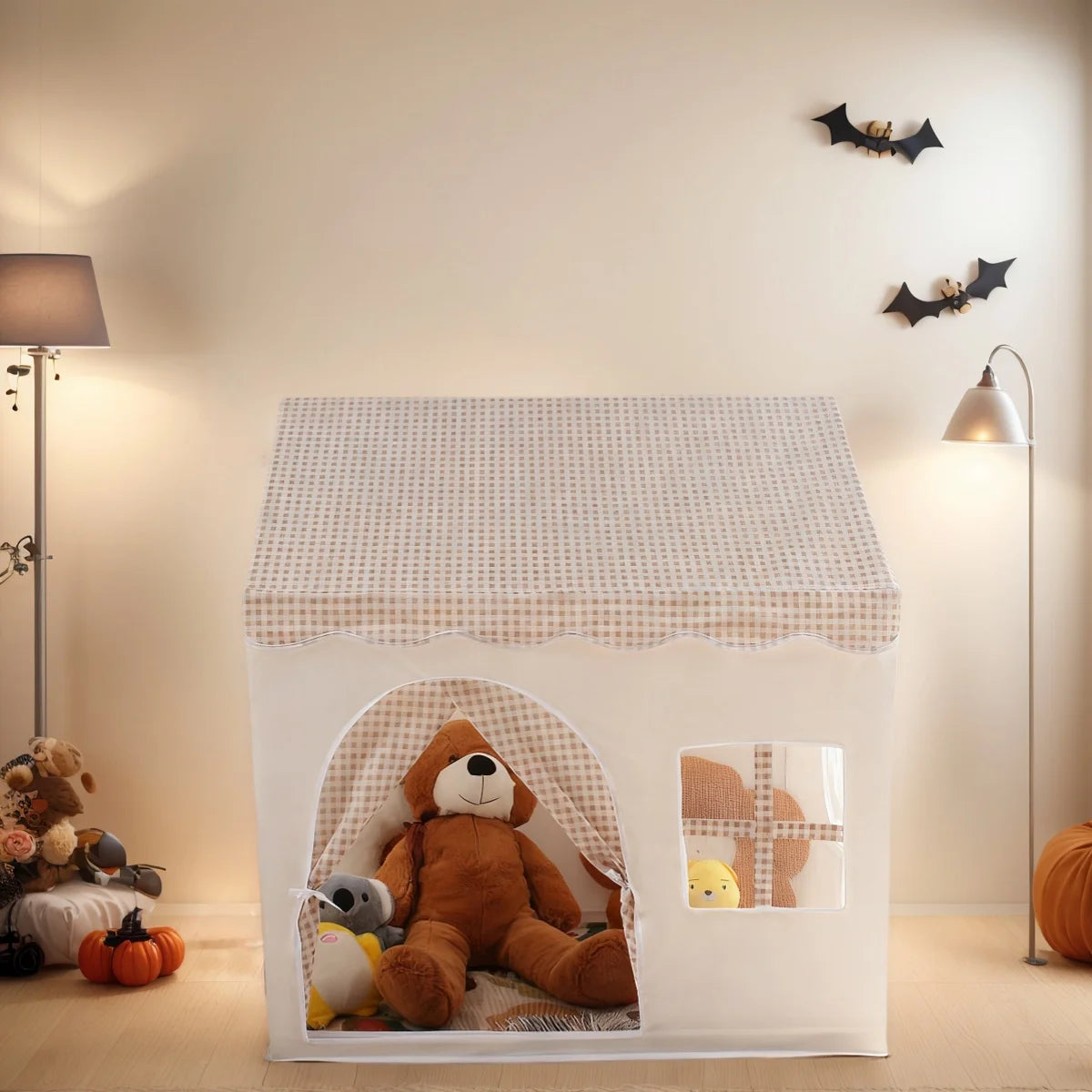 A white playhouse tent with a pink floral pattern, featuring a bear figure inside.