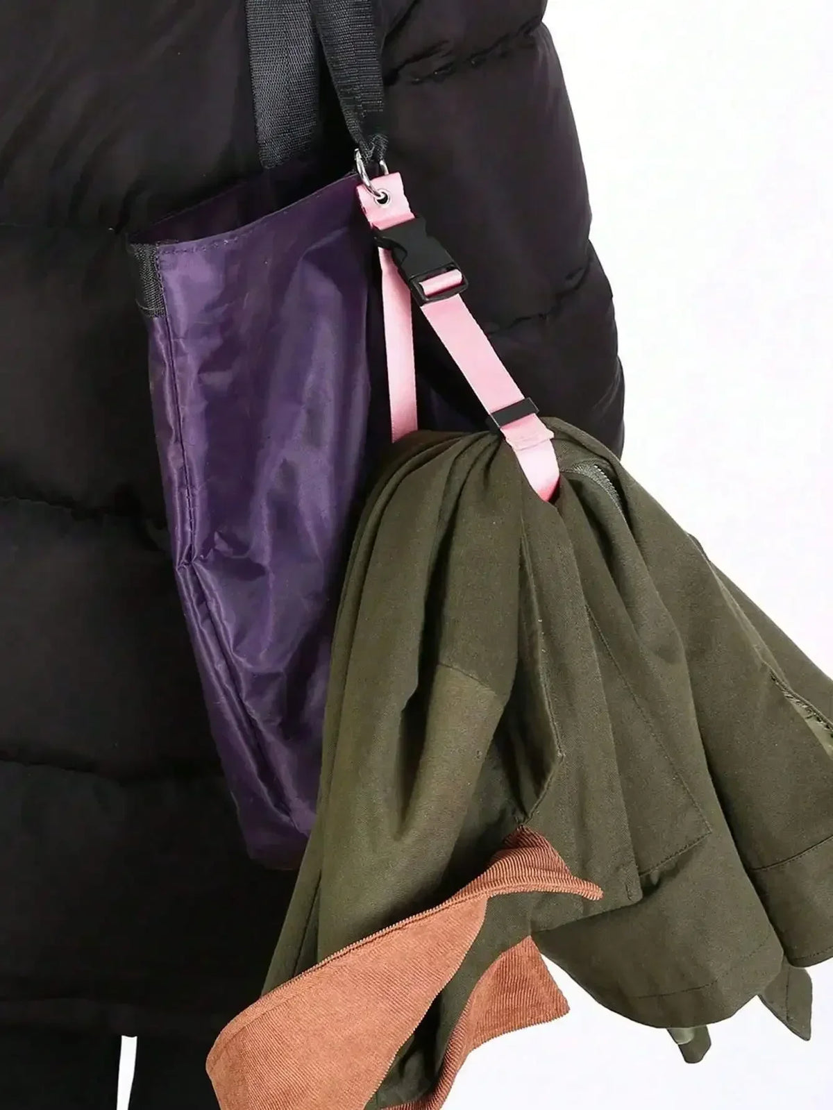 A close-up of a pink luggage strap with an ID tag attached to a dark green fabric item.