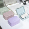 A set of pastel colored smiley face lidded soap dishes and a white towel are displayed on a white surface.
