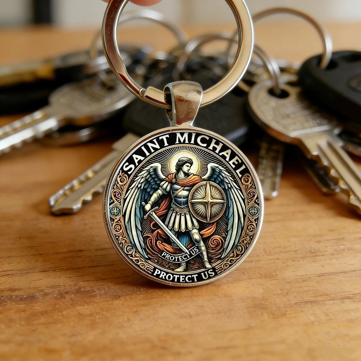 A silver key chain featuring the Saint Michael Archangel, engraved with text to protect us.