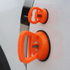 Orange heavy-duty suction cup dent puller tool mounted on a white surface.