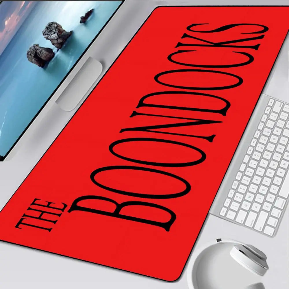 A red oversized gaming mouse pad with the title BOONDOCKS printed in black text is shown next to a white keyboard.