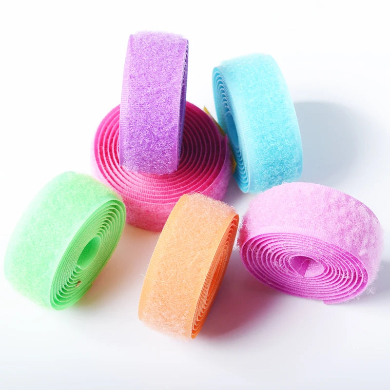 A collection of colorful sew-on hook and loop tape rolls in various shades including purple, cyan, pink, and green.