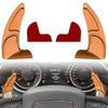 Two orange shift paddle extenders shown against a car dashboard background.