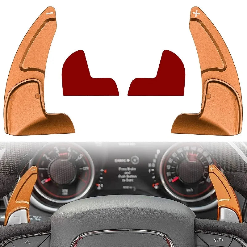 Two orange shift paddle extenders shown against a car dashboard background.