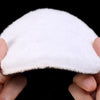 A white car polishing pad set with wool discs held between fingers against a black background.