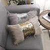 Decorative pillow covers featuring silver and gold sequins and fluffy faux fur trim on a gray sofa.