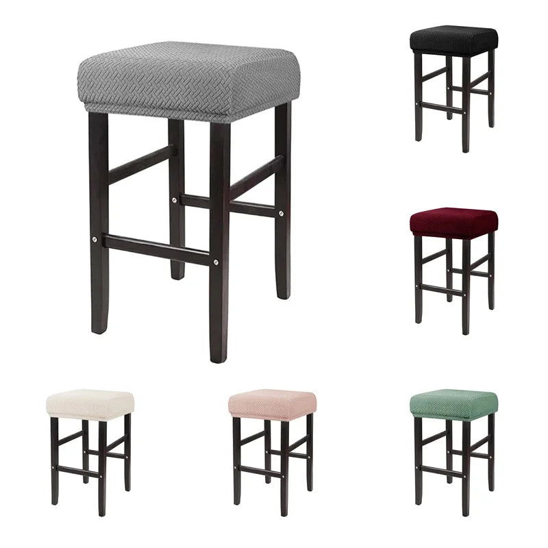 A set of four bar stools with gray, maroon, and green fabric slipcovers.