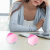Deux jouets anti-stress en forme de pêche roses posés sur un bureau à côté d'un ordinateur portable.