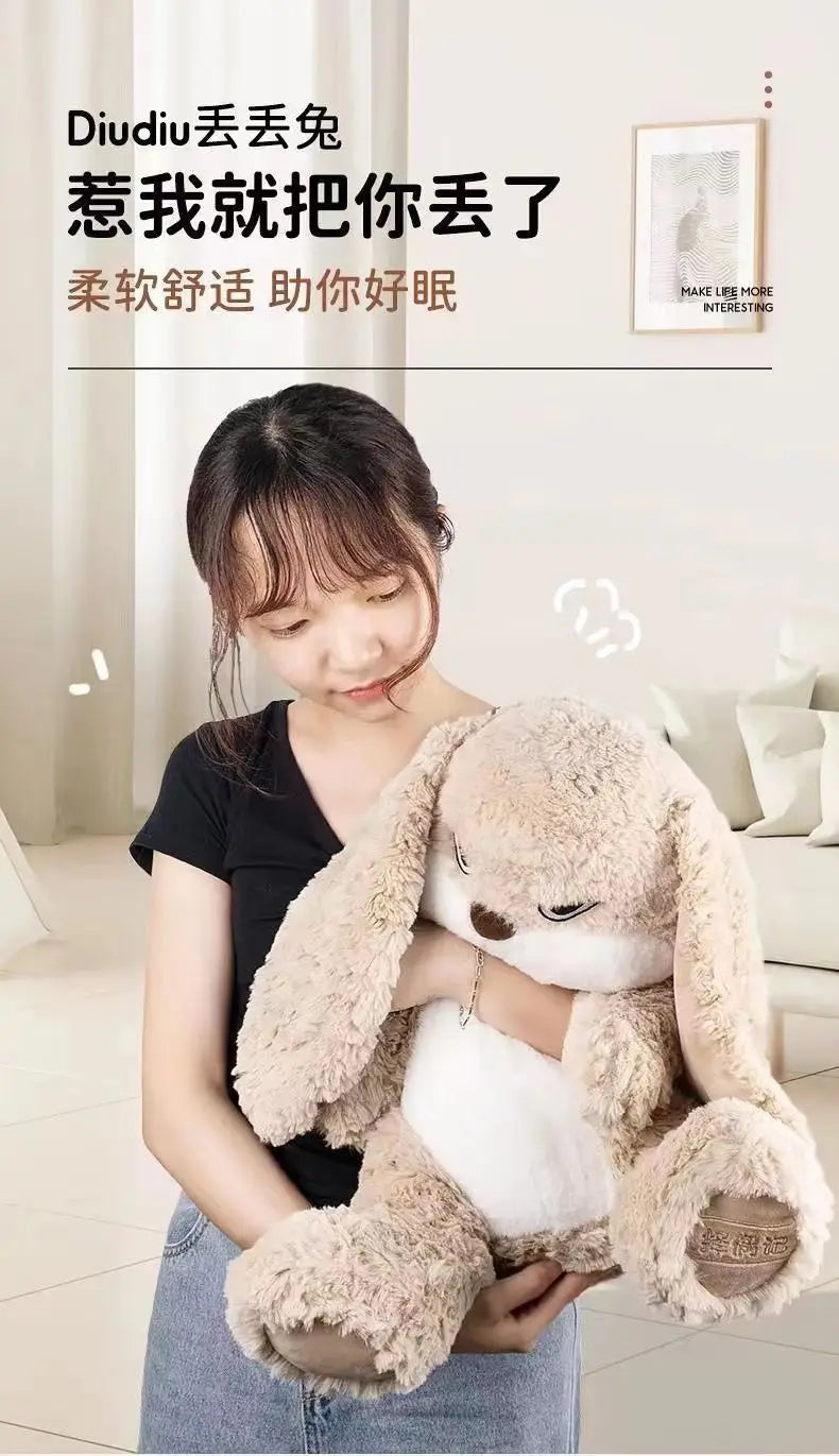 A woman is holding a large, light brown and white long-eared angry rabbit plush toy.