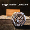 A close-up shot of a silver fidget spinner resting on a dark surface.
