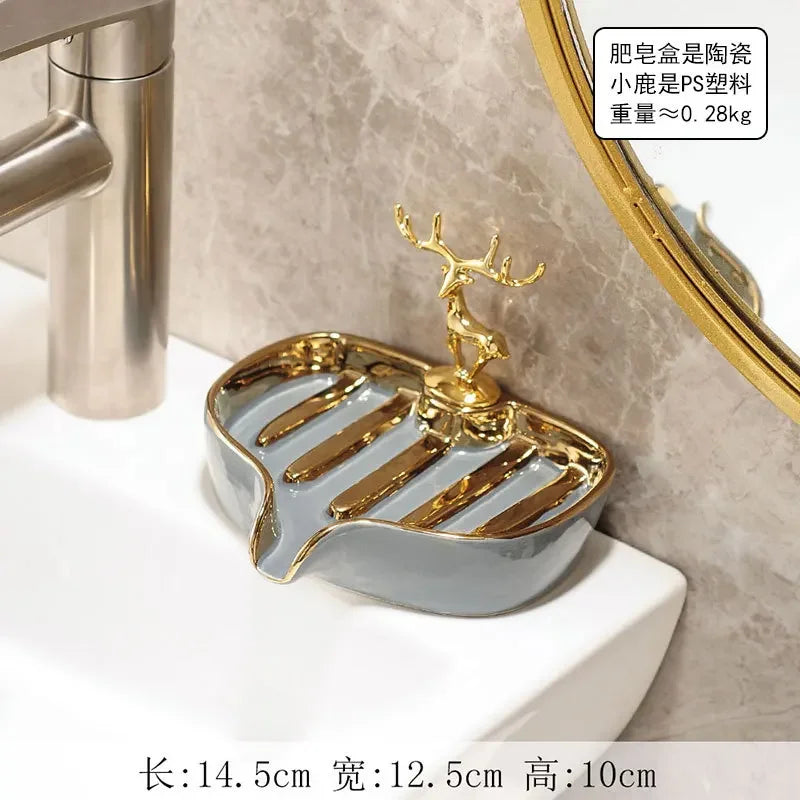 A gold leaf-shaped ceramic soap dish with a drain rack is placed on a white bathroom counter.