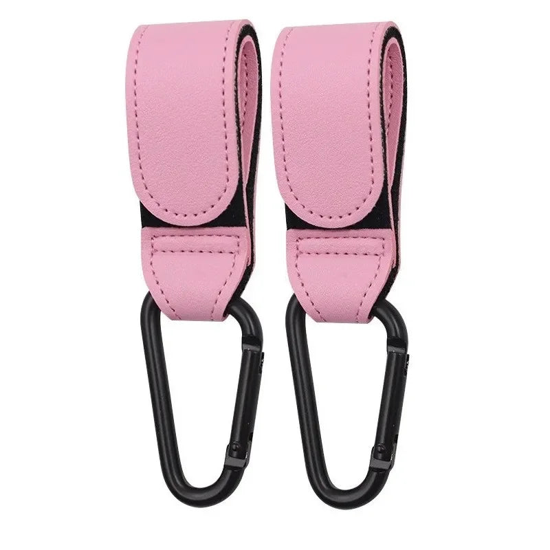 A pair of pink PU leather stroller hooks with black accents for organizing bags on strollers and prams.
