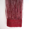 A vertical curtain made of deep red woven tassels hanging against a white background.