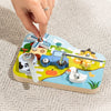 A hand is assembling a wooden farm animal toy featuring a blue tractor, a cow, and other elements with a screwdriver.