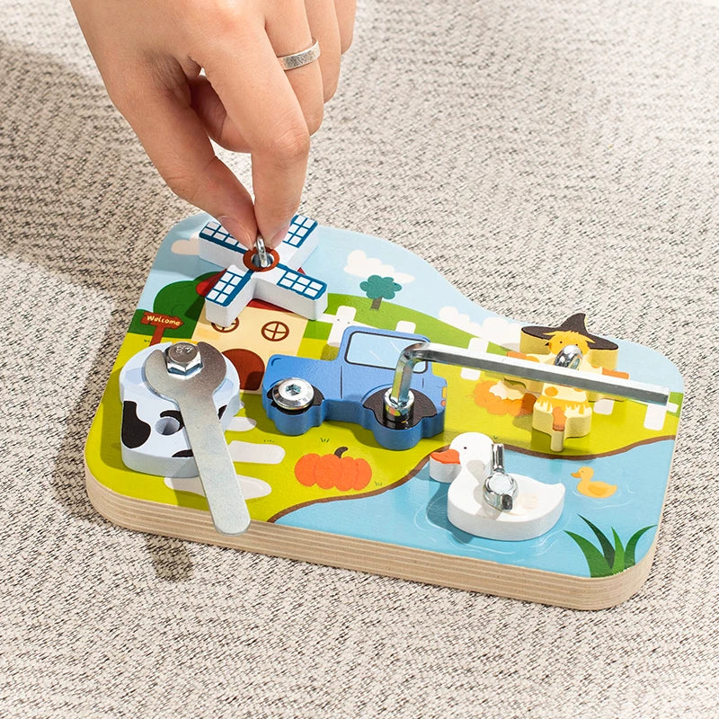 A hand is assembling a wooden farm animal toy featuring a blue tractor, a cow, and other elements with a screwdriver.