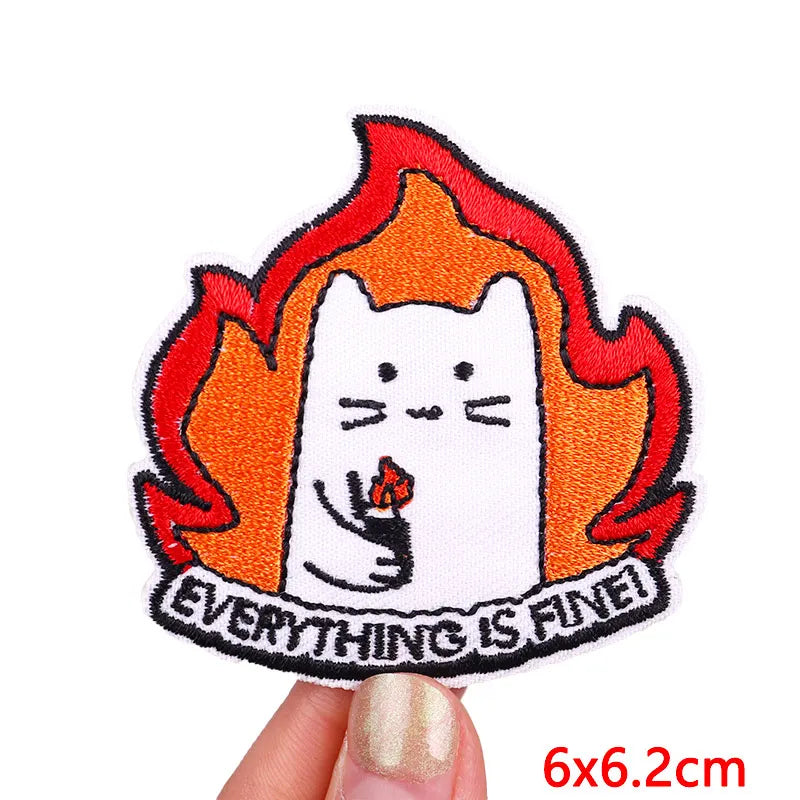 An embroidered patch featuring a white cat face surrounded by orange and red flames with the text Everything is fine.