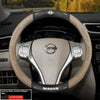 A close-up view of a beige Nissan steering wheel with carbon fiber patterned grips and controls.