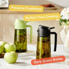 A dark green glass bottle used as a 2-in-1 olive oil dispenser and sprayer, shown next to an apple.