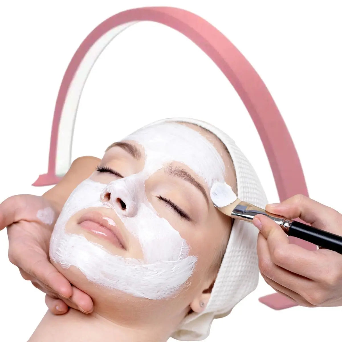 Hands apply a white facial mask to a person's face under a pink LED arc lamp.
