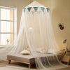 A romantic canopy mosquito net draped over a bed, featuring sheer white fabric and triangular accents.