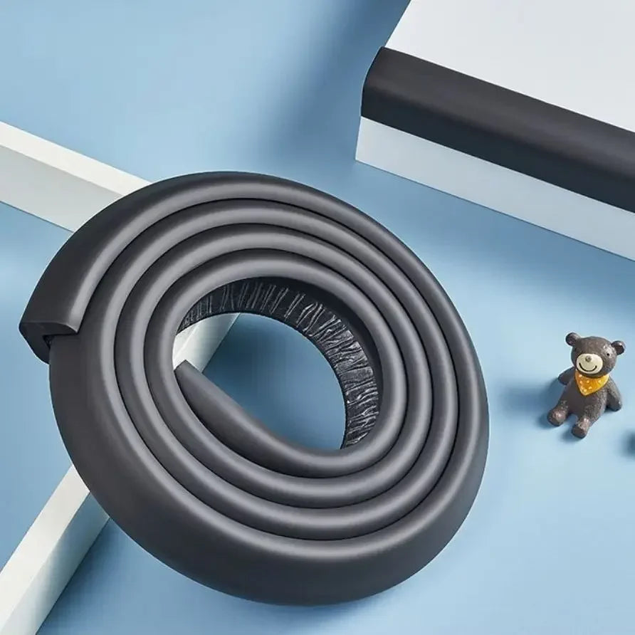 A black rubber bumper strip coiled into a circular shape on a light blue surface.