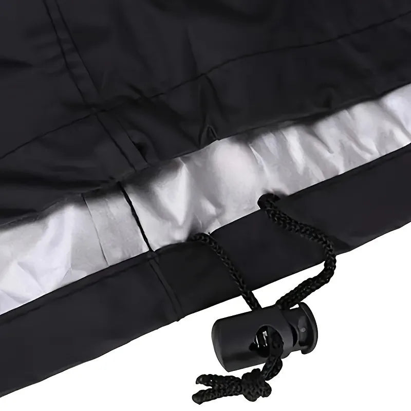 A black heavy-duty waterproof grill cover with a silver lining and a drawstring is shown.