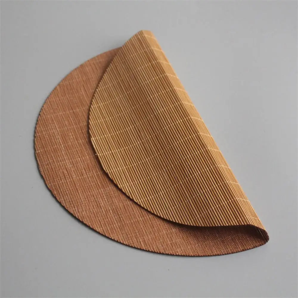 A curved, golden-brown bamboo tea mat with vertical woven texture shown in profile.