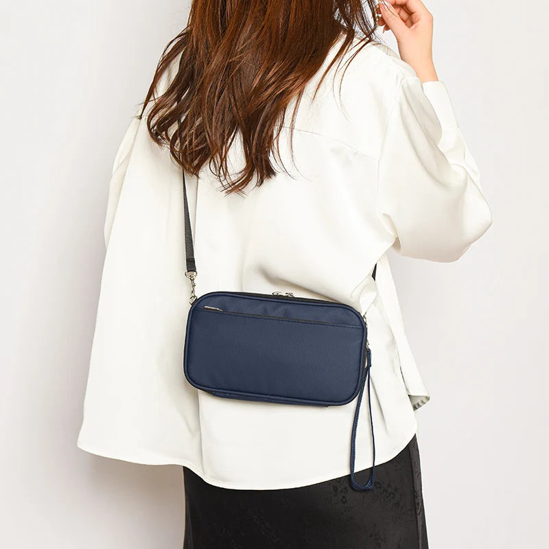 A woman wearing a white jacket is holding a navy blue passport and document organizer wallet.