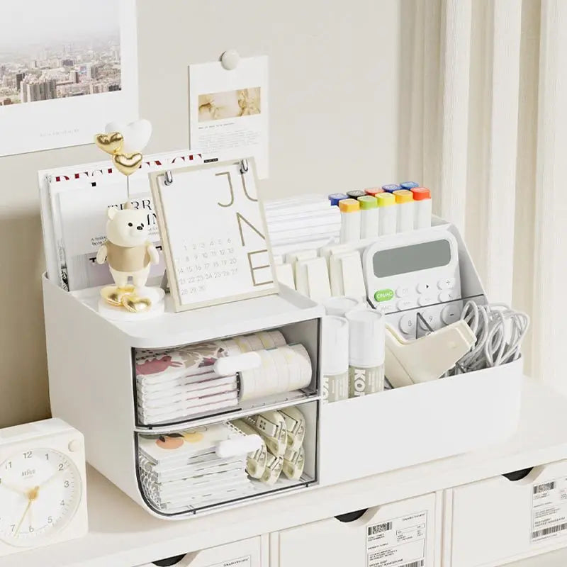 A white desk organizer with transparent drawers holds various stationery and office supplies.