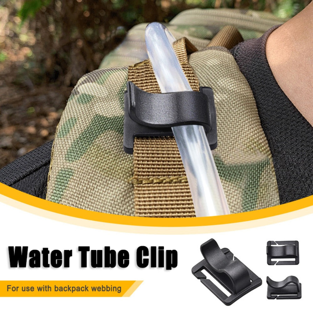 A black water tube clip is shown attached to a tan and green backpack webbing strap.
