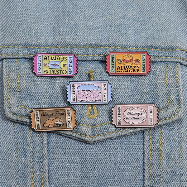 A set of vintage airline ticket enamel brooches featuring various humorous phrases like Always Exhausted and Always Hungry