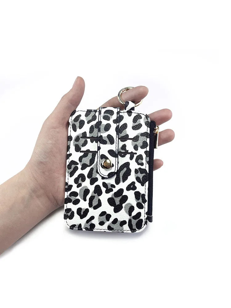 A hand holds a leopard print PU leather card holder with a coin pocket and keychain.