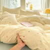 A light yellow duvet cover set with a cute dog print and matching pillowcases is displayed on a bed.