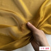 Close-up of flowing golden yellow silk chiffon fabric being held and draped.