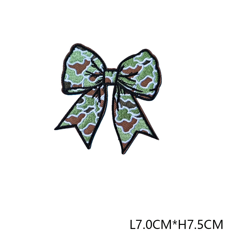 A dark olive green and brown patterned fabric bow embroidered as a hunting patch badge.