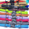 A collection of various colored adjustable backpack chest straps laid out for display.