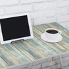 A white tablet rests on a light blue distressed wood grain table next to a white cup of coffee.