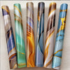A collection of vertical marble peel-and-stick wallpaper rolls in various shades of blue, green, and gold.