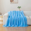 A bright blue soft and cozy brushed flannel throw blanket draped over a white sofa.