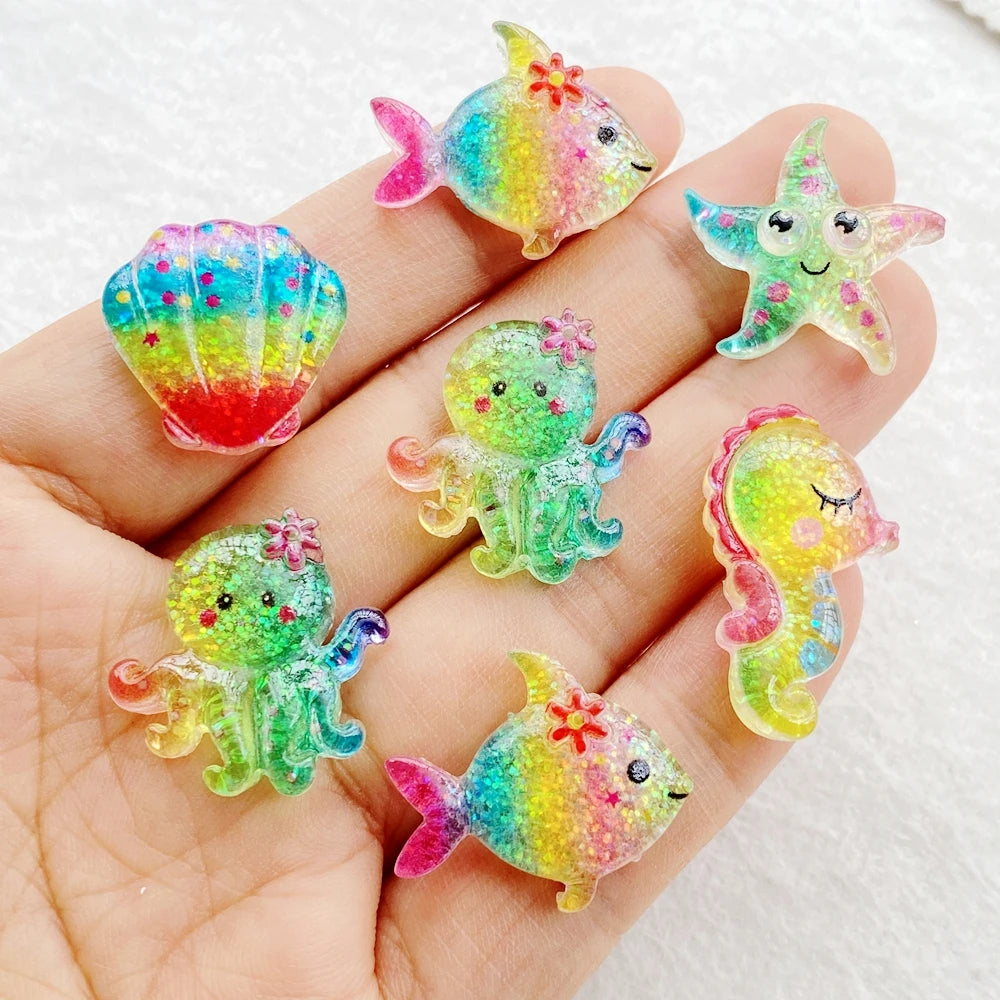 Hand holding colorful resin charms shaped like fish, starfish, and sea creatures for crafting