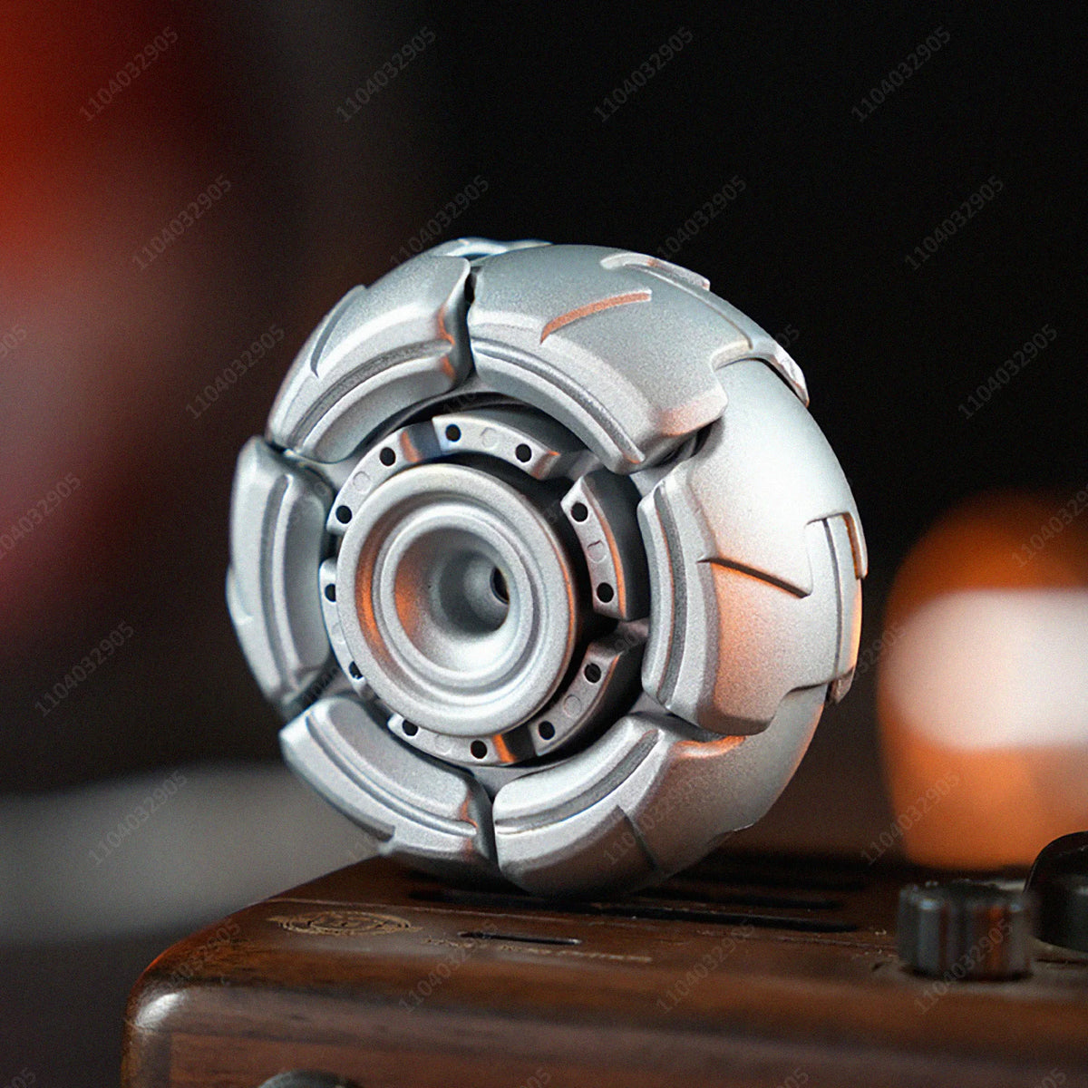 A silver stainless steel fidget spinner resting on a dark wooden surface.