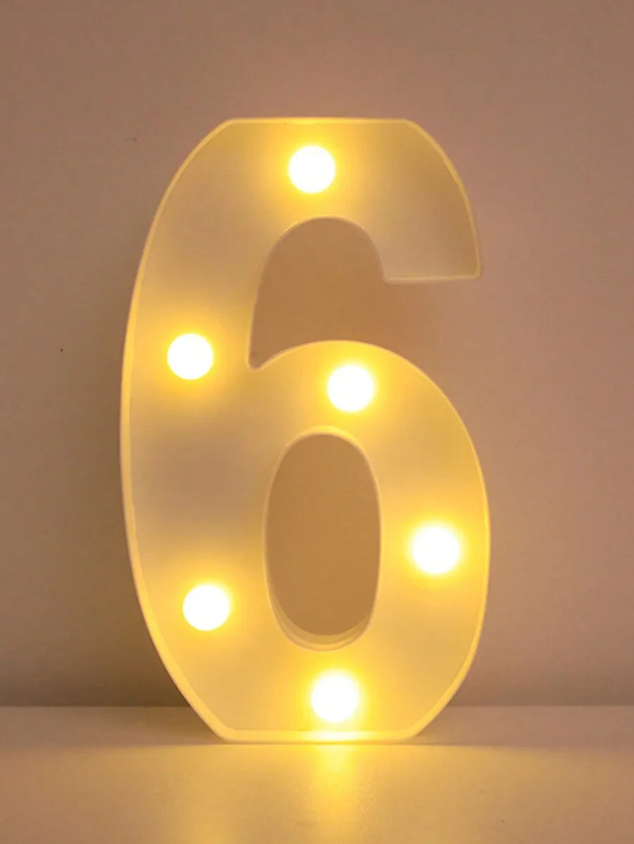 A glowing six letter night light illuminating a white wall.