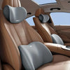 Interior view of a car seat showing memory foam headrest and lumbar support pillows in tan leather upholstery
